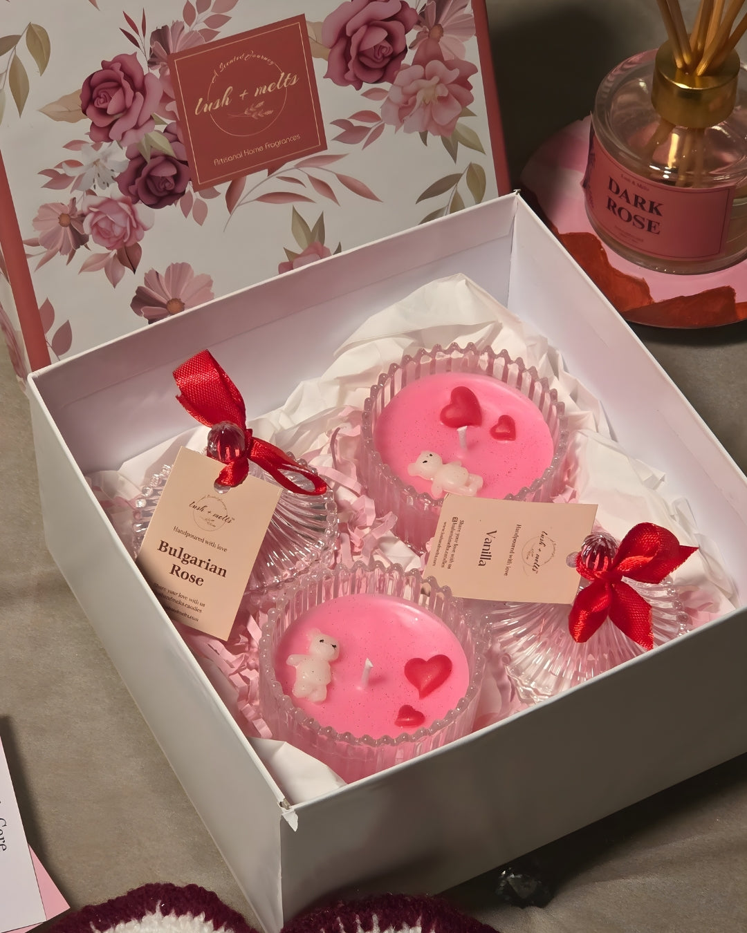 Pink candles with heart and bear designs in a decorative box with floral packaging.