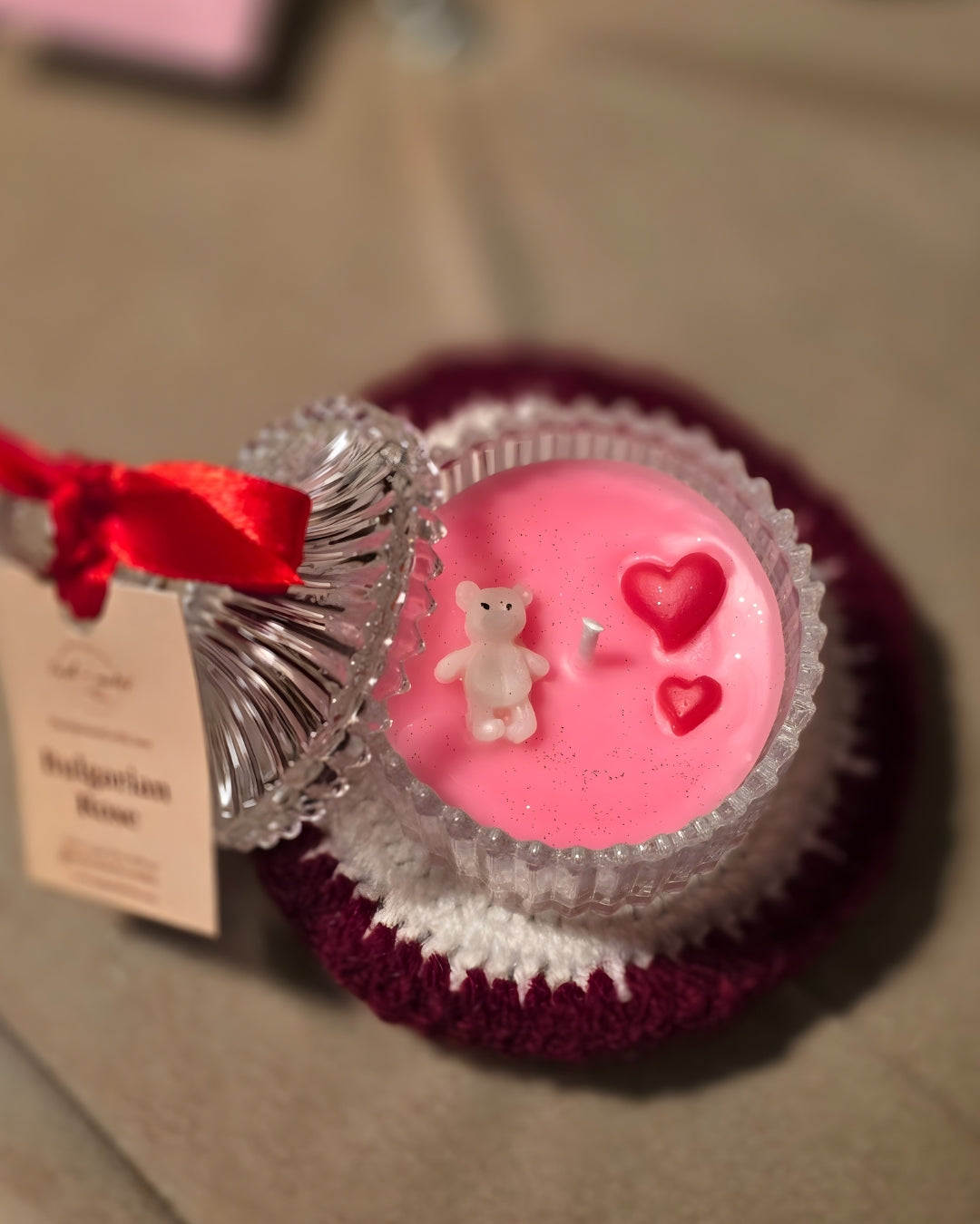 Decorative item resembling a cupcake with pink filling, teddy bear, and hearts on a textured surface.